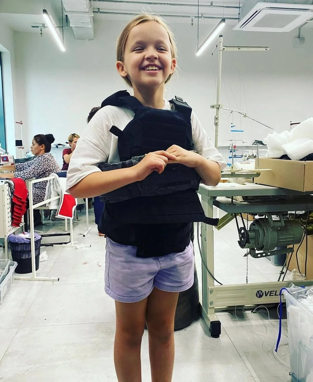 A girl trying on an IRONKID children's vest in the sewing workshop